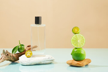 A stack of kumquats and limes displayed with a perfume bottle standing on a block of stone. Lime...