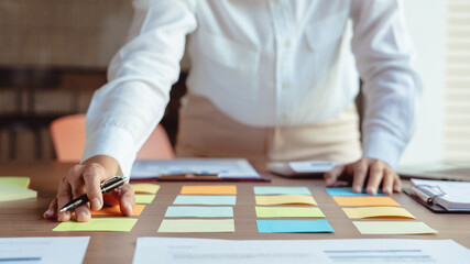 Businesswoman writing data in sticky notes on table to sharing ideas about strategy of new business