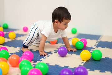 Fototapeta na wymiar infant baby playing colorful balls in playpen
