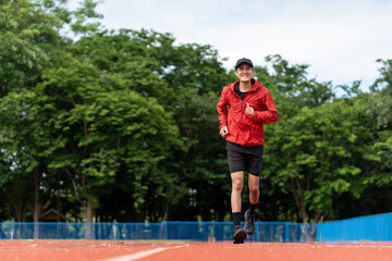 Attractive Young indian man wearing sportswear running on track at sport stadium. Asian Fit man...