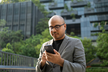 Senior manager business man in suit with cell phone at the buildings downtown. Confident man using...