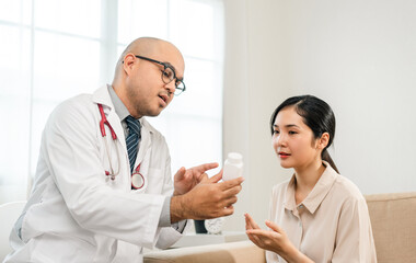 Asian Doctor and patient discussing consulting  with digital tablet. Patient meet talking with Doctor giving pills bottle to woman at hospital. Medicine and health care treatment result in clinic
