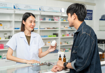 Obraz premium Pharmacist recommends medicines to customers.Taking the questions of medication. Asian female pharmacist giving prescription medications to customers at drugstore shelves.