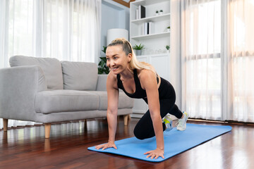 Athletic and active senior woman doing exercise on fit mat with plank climbing at home exercise as concept of healthy fit body lifestyle after retirement. Clout