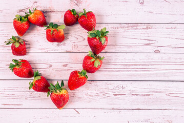 Making shapes with strawberries with rustic background, strawberry heart