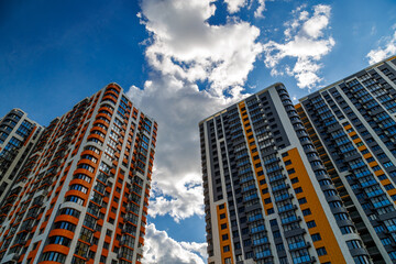 freshly built high rise apartment buildings on blue sky background with white clouds. - obrazy, fototapety, plakaty