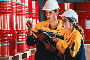 Two factory workers or inventory inspector conduct professional inspection on hazardous chemical barrels in warehouse, chemistry storage workplace and industrial profession concept. Exemplifying