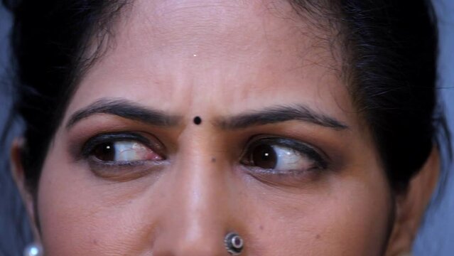 Closeup shot of an Indian middle-aged woman's  eyes - rolling her eyes  eye exercises  eye liner  Indian face. An extreme-closeup of an Indian lady looking straight into the camera