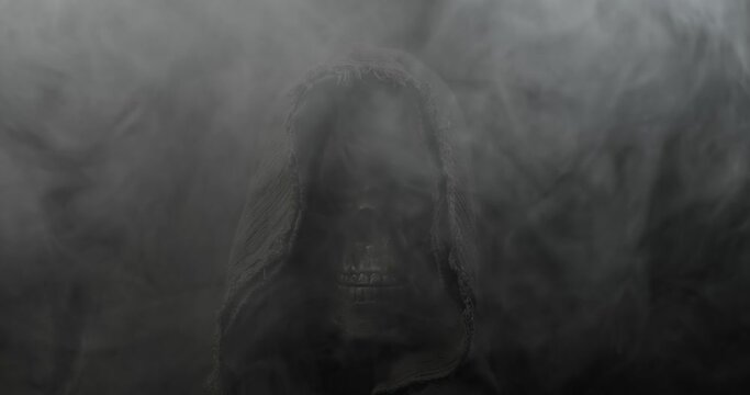 Smoke surrounding mysterious hooded figure with spooky human skull slowly fading into darkness. Scary grim reaper representing death, horror, or frightening Halloween silhouette.