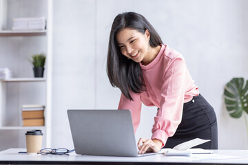 Asian Business woman using calculator and laptop for doing math finance on an office desk, tax, report, accounting, statistics, and analytical research concept
