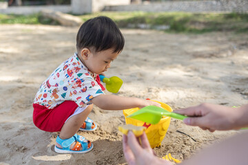 An Asian Chinese baby boy on the beach in the toys for the sand. Children's games. Games on the beach