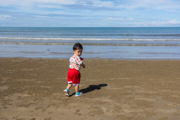 Happy little boy having a fun time at and running at beach