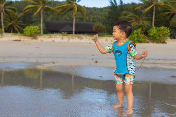 Happy Asian Chinese child playing in the beach. Kid having fun outdoors. Summer vacation and...