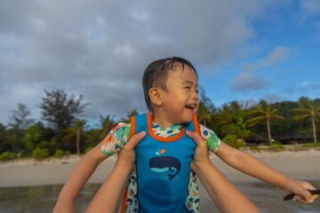 Happy Asian Chinese child playing in the beach. Kid having fun outdoors. Summer vacation and healthy lifestyle concept