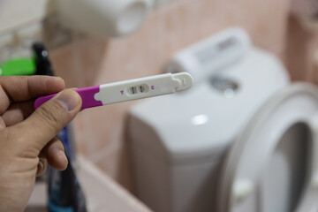 Close up of woman hands holding positive home pregnancy test - obrazy, fototapety, plakaty