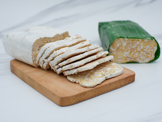 raw tempeh or tempe. tempeh slices on wooden cutting board. Tempeh is made from fermented soybeans