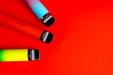 Colorful disposable electronic cigarettes on red background