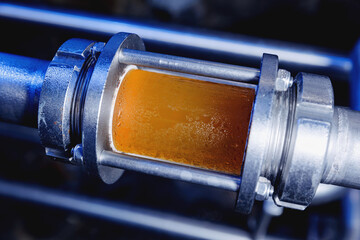 Brewing equipment for quality control, sight glass full of golden beer on stainless steel pipe....