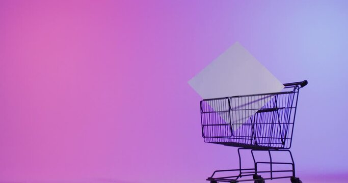 Video of shopping trolley and canvas with copy space over neon pink background