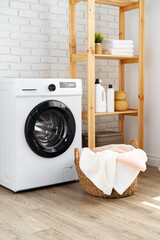 Fototapeta na wymiar Laundry room with washing machine and basket with laundry