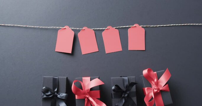 Video of gift tags on string, gift boxes with ribbons and copy space on black background