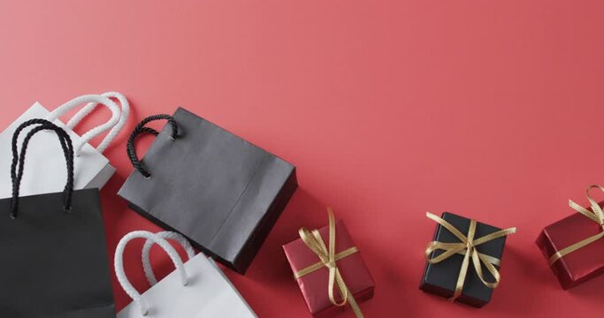 Video of gift bags and gift boxes with ribbon and copy space on black background