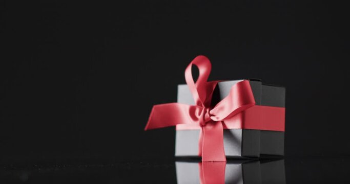Video of gift box with red ribbon and copy space over black background