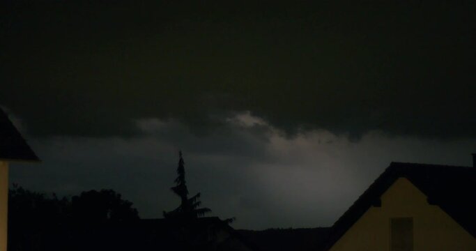 Looking out of a window at night during a thunderstorm. A lot of lightning flashing over the night sky in a very short time period, almost looking light flash lighting.