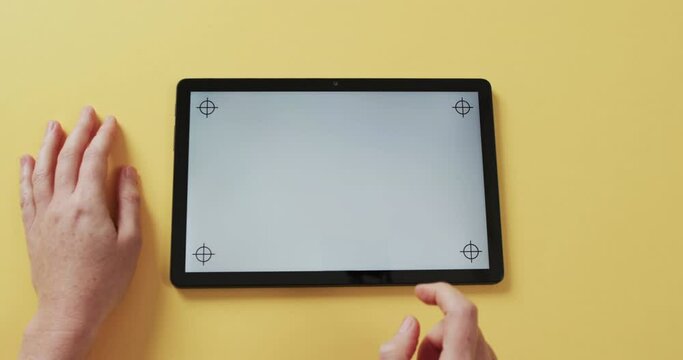 Video of hands of caucasian woman and tablet with blank screen on yellow background