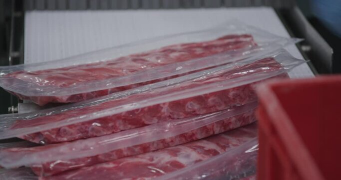 Ribs coming out of packaging machine. The ribs are covered with see trough plastic.