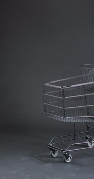 Vertical video of shopping trolley with copy space over grey background