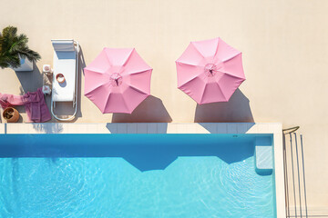 swimming pool in the resort. Summer Aesthetics: Two Pink Umbrellas and a Sun Lounger by the Pool—Perfect for Seasonal and Leisure Themes