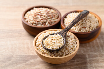 Thai brown rice seed in wooden bowl with spoon, Organic rice, Healthy food ingredient