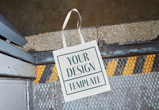 Mockup of customizable tote bag lying on industrial elevator floor, camera flash