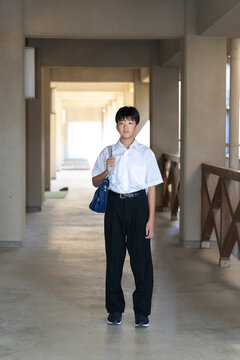 学校の校舎と学生服を着た男子学生