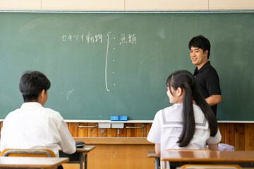 学校の教室の教壇に立つ男性教師