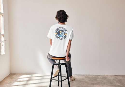 Mockup of woman wearing t-shirt with customizable color sitting on stool, rear view
