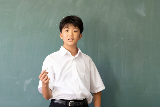 教室の黒板の前に立つ男子中学生