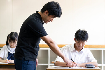 学校の教室で教わる生徒と教える先生