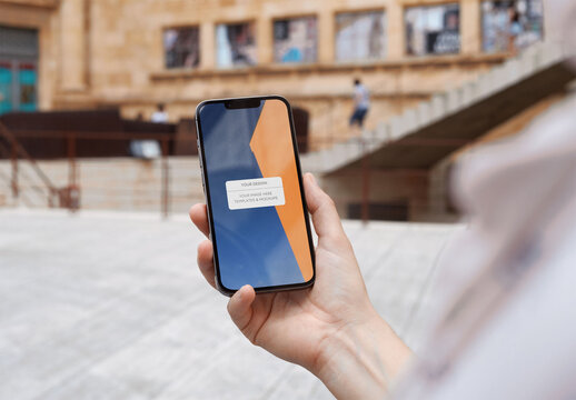 Mockup of person holding mobile phone with customizable screen in a city