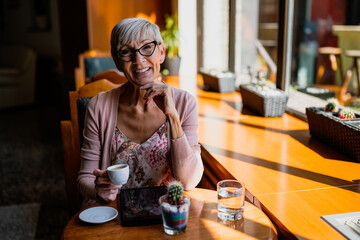 Mature woman is sitting in cafe and relaxing.
