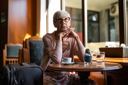 Mature woman is sitting in a cafe at the airport, waiting for boarding.