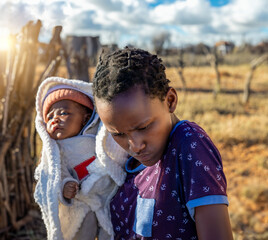 teenage years, african girl holding a baby, Botswana village, backyard view