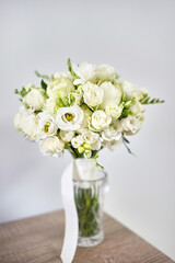 A bouquet of beautiful white roses in a vase on the table. Preparation for the wedding celebration.
