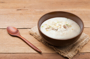 Traditional chinese porridge rice gruel in brown bowl  with wooden spoon