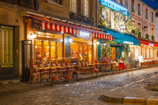 PARIS, FRANCE - APRIL 16, 2023: Cozy restaurants at Place du Tetre by night. Small cobbled square in Montmartre, Paris, France.
