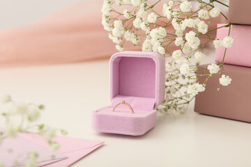 Wedding ring in case and flowers on white background, close up