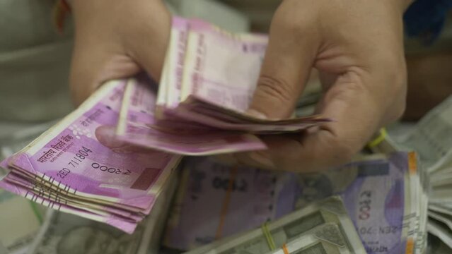 An Indian businessman counting 2000 Rupee banknotes, Cash in Hand Closeup, India, Selective focus