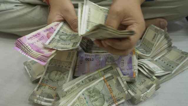 A South Asian businessman counting 2000 and 500 Rupee banknotes, Stack of Indian banknotes, Cash in Hand Closeup, India