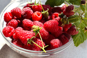 Vitamin berry: ripe raspberries in a glass bowl on the kitchen table, close-up